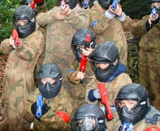 Participants in protective masks and overalls during a paintball activity