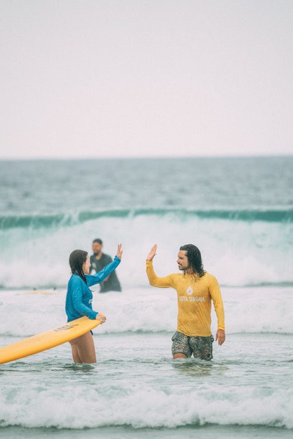 A surf instructor high fiving his student during a surf lesson in Sri Lanka.