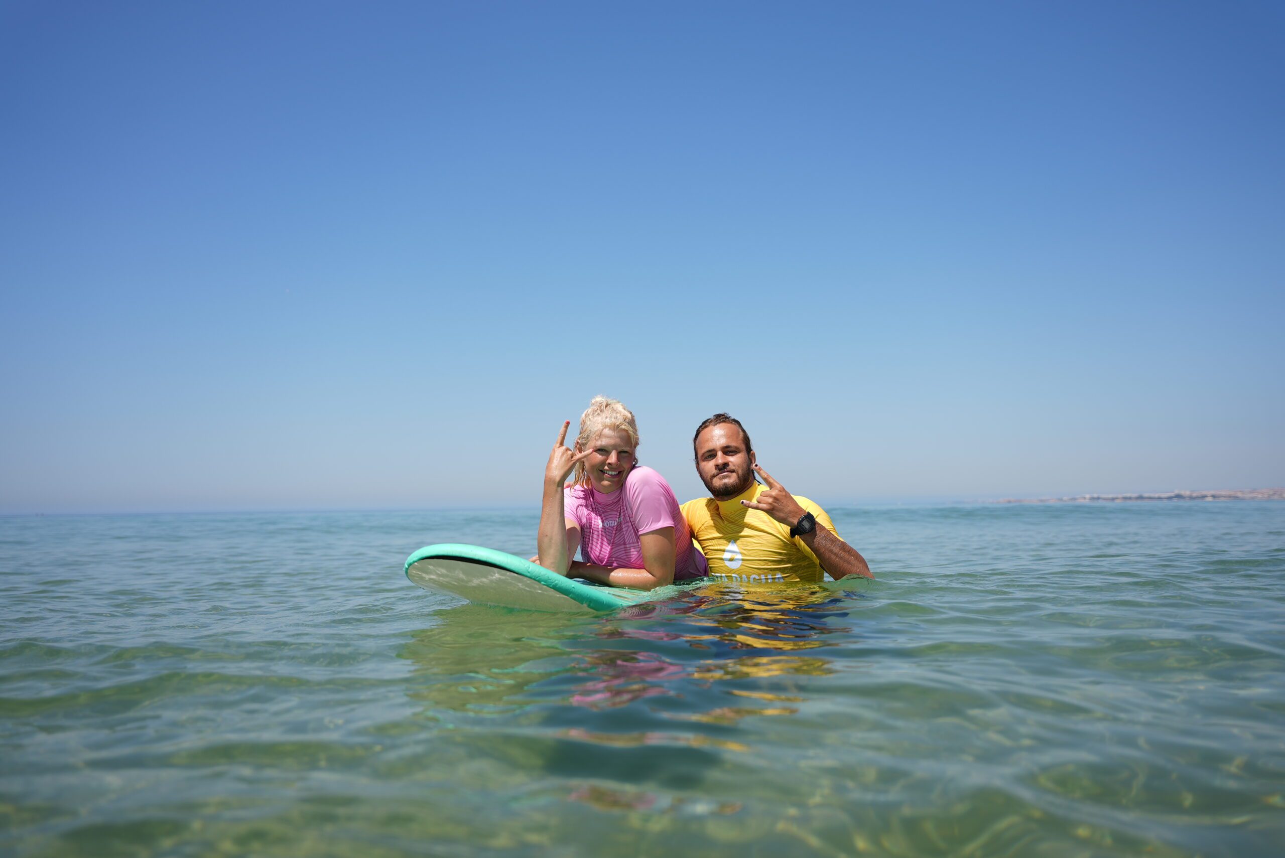 A surfer girl smiling inside of the water in a surf camp
