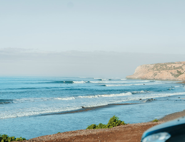 Point break waves rolling toward a rocky sandy headland on the coast