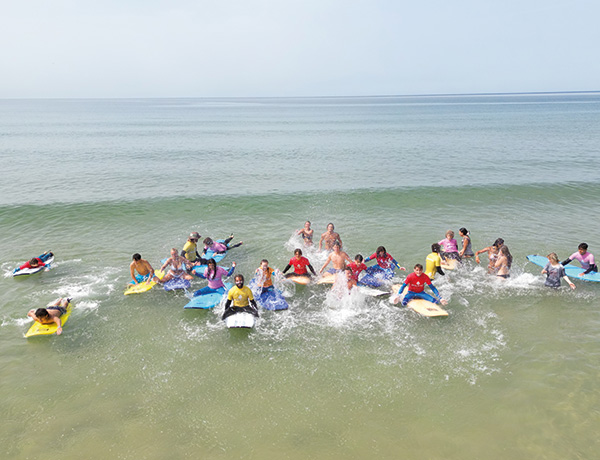 Group of young surfers riding whitewater waves together on boards