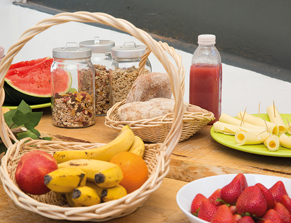 Wooden table with fruit baskets, granola jars, bread, strawberries and juice for camp meals