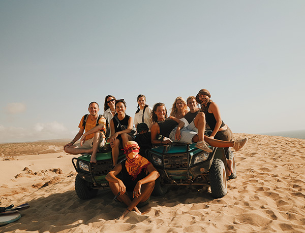 Group posing on two quad bikes atop a sand dune in Morocco