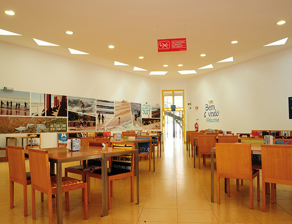 Dining hall with long wooden tables where junior surf camp guests eat together