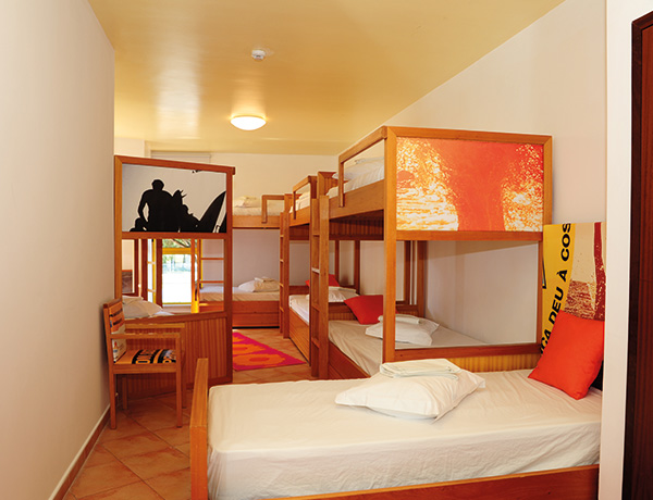 Bunk-bed room with orange decor and surf artwork at our junior surf camp