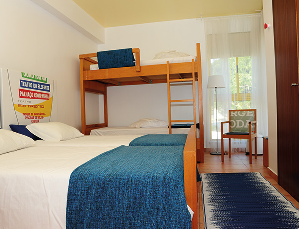 Shared room with bunk beds and blue bedspreads at our junior surf camp