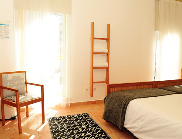 Bedroom with a ladder shelf and armchair at our junior surf camp accommodation