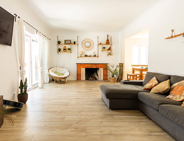 Bright living room with a fireplace and corner sofa in our Costa da Caparica surf house