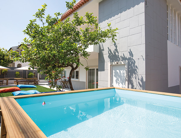 Pool and wooden deck shaded by a tree at our surf camp Portugal house