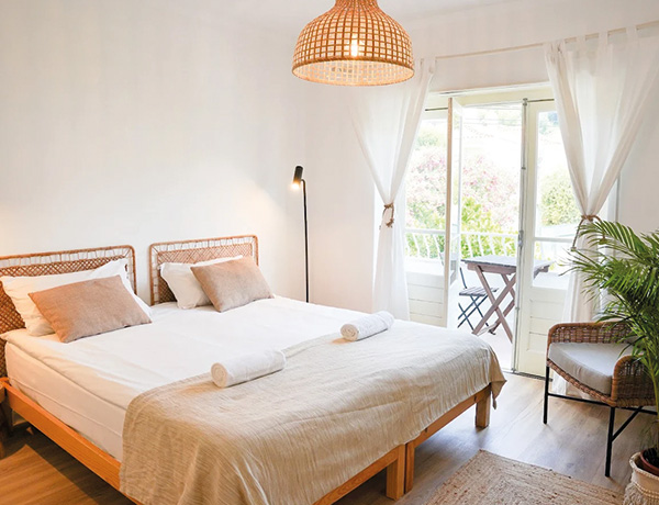 Twin bedroom with a rattan pendant lamp and balcony doors in our surf camp Portugal house