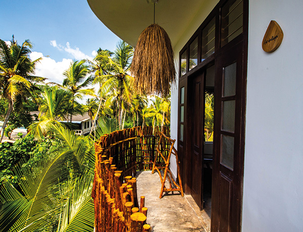 Balcony with a woven pendant lamp and palm views at our Ahangama surf camp