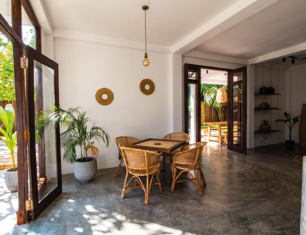 Dining area with rattan chairs and polished floors inside our Sri Lanka surf house