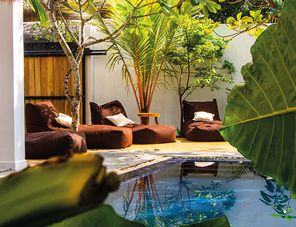 Bean bags on the poolside deck framed by tropical plants at our Sri Lanka surf house