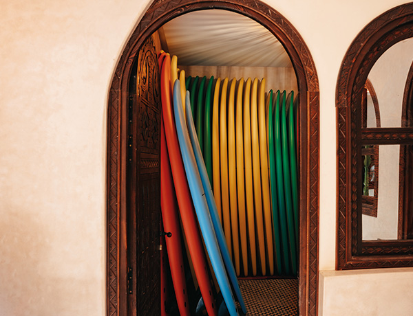 Colourful surfboards racked behind a carved arched doorway at our surf camp Morocco house