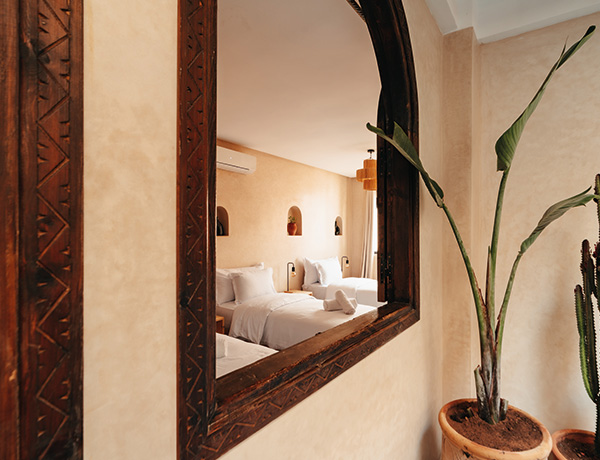 Carved wooden mirror reflecting a twin bedroom in our Tamraght surf house
