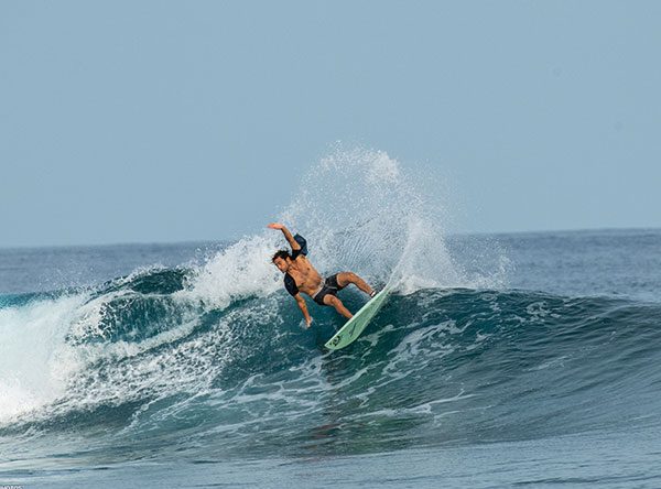 Surfer carving a turn on a wave with spray flying behind him