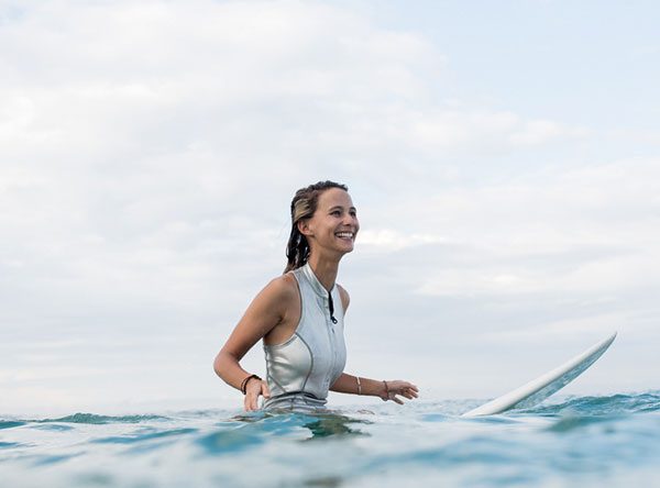 Woman smiling while sitting on a surfboard in the ocean