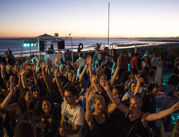 Crowd dancing at a beachfront sunset party during our new year surf camp