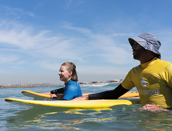 Instructor guiding a student on a foam board, included in our surf camp packages