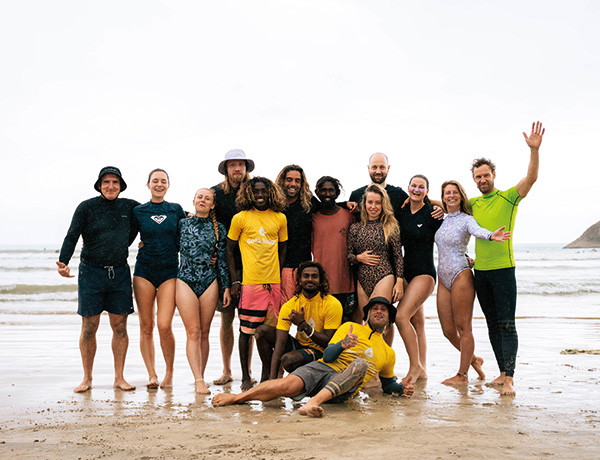 Group posing on the beach after a lesson during a corporate surf retreat