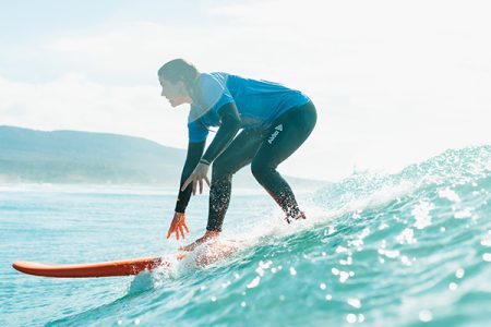 Woman riding a wave on an orange board at our surf camp on the Moroccan coast