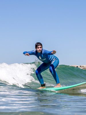 Young surfer in a blue wetsuit riding a small breaking wave