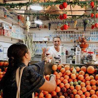 Vendor serving fresh orange juice at a Moroccan market stall piled with oranges