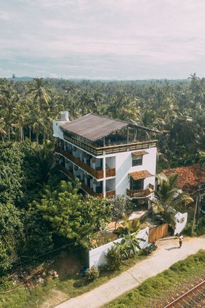 Aerial view of a multi-storey surf camp building surrounded by palm trees in Sri Lanka