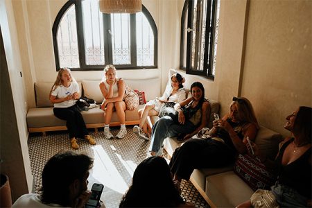 Friends laughing in a Moroccan riad lounge on one of our group surf trips